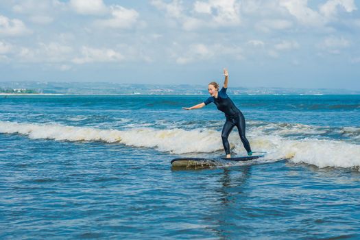 Joyful young woman beginner surfer with blue surf has fun on small sea waves. Active family lifestyle, people outdoor water sport lesson and swimming activity on surf camp summer vacation.