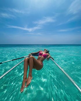 A beautiful slender tanned woman with long hair in a swimsuit in the Maldives is resting.