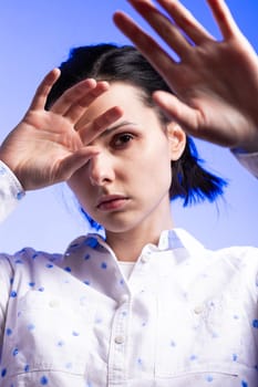 brunette woman in a white shirt with polka dots, on a blue background. High quality photo