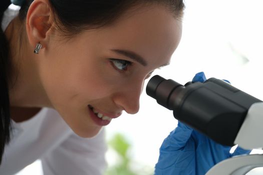 Portrait of pharmacy scientist working with professional microscope in technology lab. Laboratory with research equipment for virus study or vaccine development