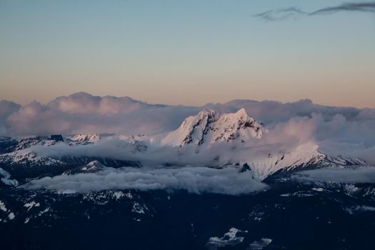 Aerial Landscape View of Garibaldi Mountain covered in Clouds during a colorful Sunset. Picture taken in Squamish, British Columbia, Canada.