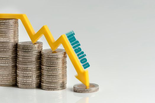 Decrease in inflation. The recession of the economy and the euro. The concept of economic collapse and stock market collapse in the euro area. Stacks of coins and a graph arrow pointing down