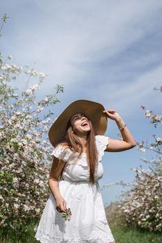 Spring concept. Nature.Young caucasian woman in white summer dress enjoying the flowering of an apple trees, walking in spring apple gardens