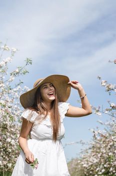 Spring concept. Nature.Young caucasian woman in white summer dress enjoying the flowering of an apple trees, walking in spring apple gardens