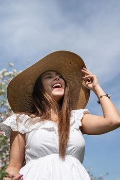 Spring concept. Nature.Young caucasian woman in white summer dress enjoying the flowering of an apple trees, walking in spring apple gardens