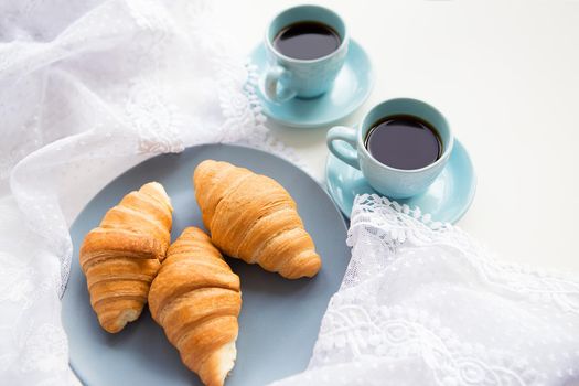 two cups of coffee with croissants on the background laces