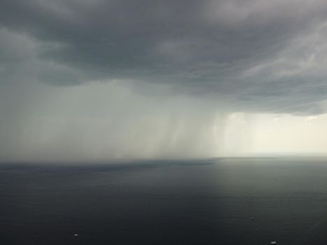 Aerial view footage of rain clouds over sea ocean Black clouds in bad weather day over sea surface High angle view nature view Apocalypse. Storm Large freight dark gloomy rain clouds over a calm sea.