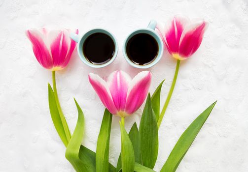 two cups of coffee and three beautiful pink tulips. valentine card