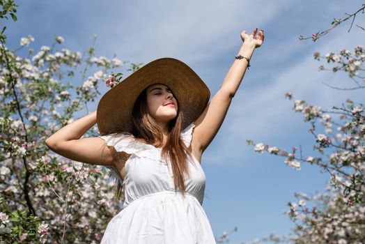 Spring concept. Nature.Young caucasian woman in white summer dress enjoying the flowering of an apple trees, walking in spring apple gardens