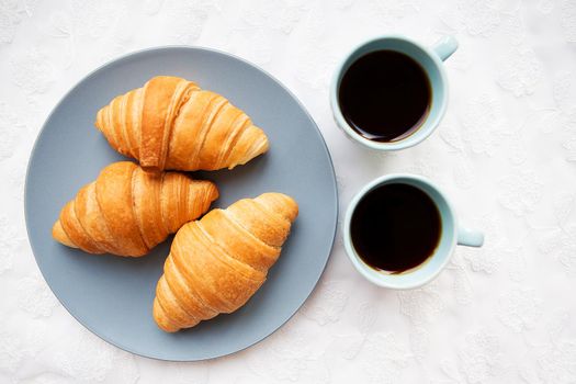 two cups of coffee with croissants on the background of laces on a white background, close-up