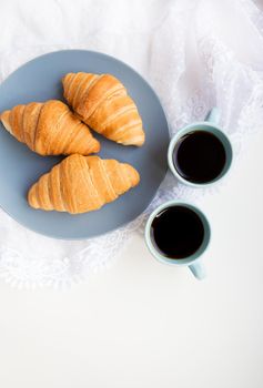 two cups of coffee with croissants on the background of laces on a white background