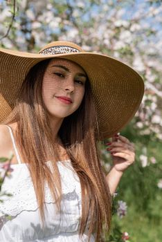 Spring concept. Nature.Young caucasian woman in white summer dress enjoying the flowering of an apple trees, walking in spring apple gardens