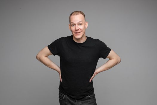 picture of handsome caucasian male keeps his hands on the belt and looks aside isolated on grey background