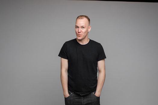 picture of handsome caucasian male keeping hands in the pockets isolated over the grey background