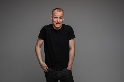 picture of handsome caucasian male keeping hands in the pockets isolated over the grey background