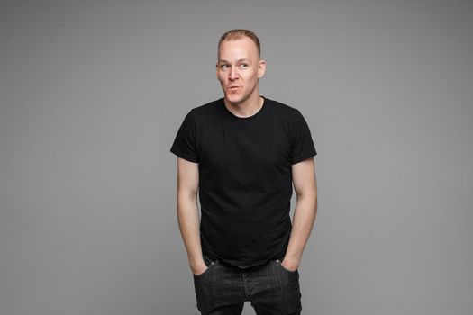 picture of handsome caucasian male keeping hands in the pockets isolated over the grey background