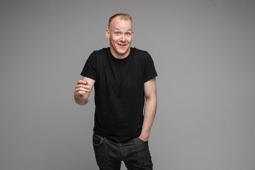 picture of handsome caucasian male keeping hands in the pockets isolated over the grey background