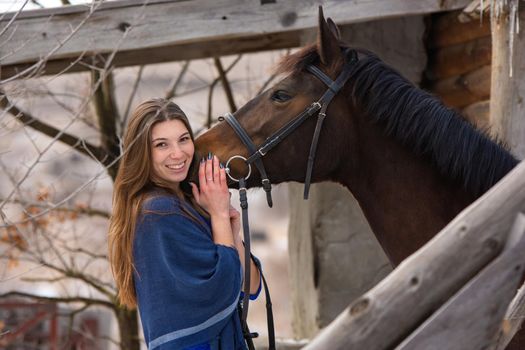 Portrait of a happy girl hugging a horse, the girl joyfully looks into the frame a