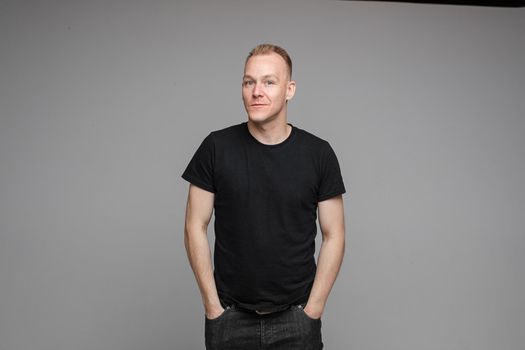 picture of handsome caucasian male keeping hands in the pockets isolated over the grey background