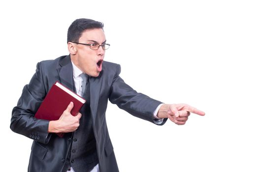 Furious male teacher in formal suit and eyeglasses with book pointing away while swearing isolated on white background in light studio