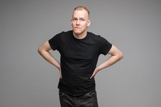 Waist-up photo of adult man in black shirt making a beaconing gesture with his hand and looking at the camera