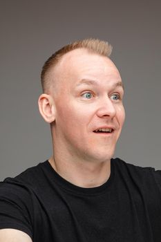 Studio close-up photo of Caucasian man in black shirt looking surprised