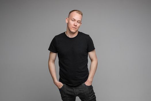 Portrait of Caucasian blond man in black clothing showing disbelief shrugging his shoulders and pointing at camera with his hand asking what is the problem.