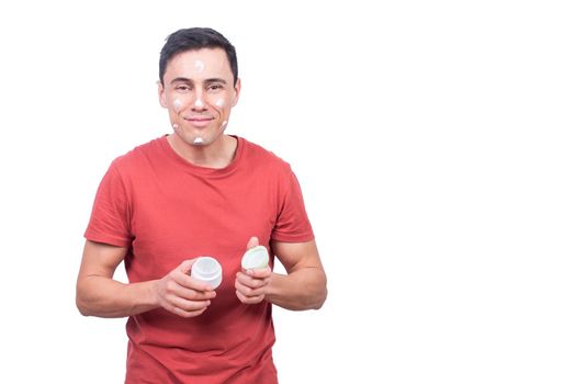 Positive male with anti aging facial cream looking at camera with smile during daily skin care routine isolated on white background