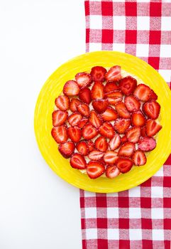 Bright and delicious strawberry cake on a red napkin in a cage.