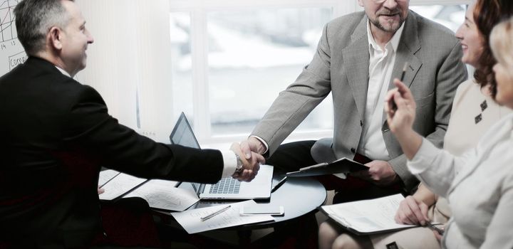 business partners shaking hands before business meeting in office