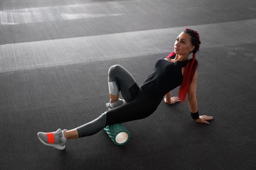 Woman massaging foam roll leg gym myofascial release exercise rolling, trigger points Middle adult caucasian woman sportswoman uses roller massager for relaxation, stretching muscles and back pain.