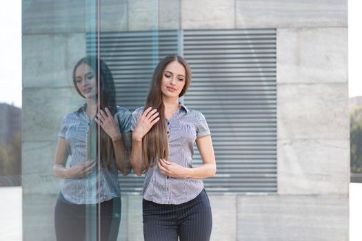 Business woman 35 years dressed stripe shirt with long hair standing near office building outdoor with cloud reflection on windows Caucasian female business person outside
