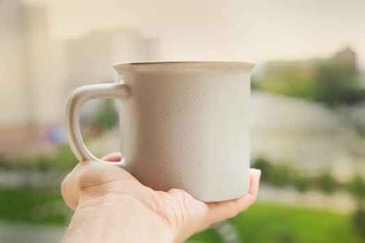 Hand holding cup with urban landscape on backckground