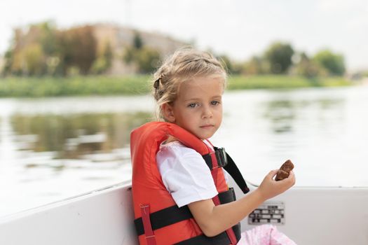Little girl dressed life vest ride pleasure boat on city river Sunny summer day Caucasian female child swimming on boat dressed orange protective vessel Summer day
