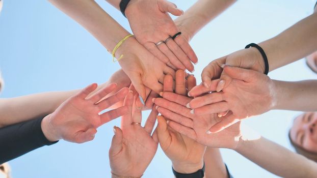 Cheerful girls join hands together as a sign of unity and joint successful work. Teamwork stacking hand concept