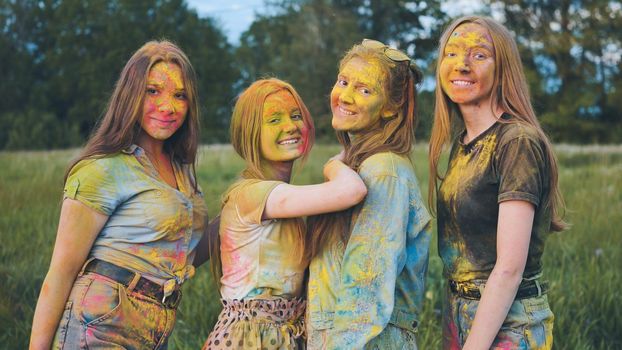 Cheerful girls posing smeared in multi-colored powder