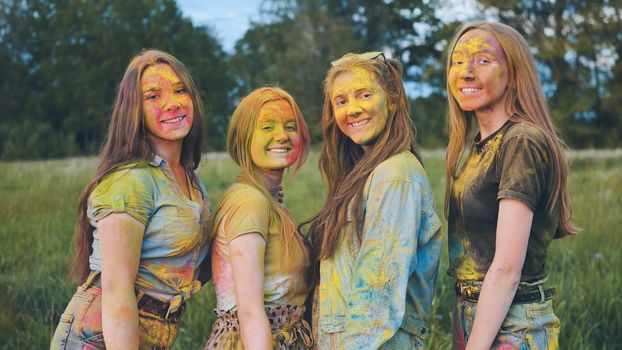 Cheerful girls posing smeared in multi-colored powder