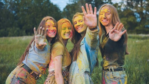 Cheerful girls posing smeared in multi-colored powder