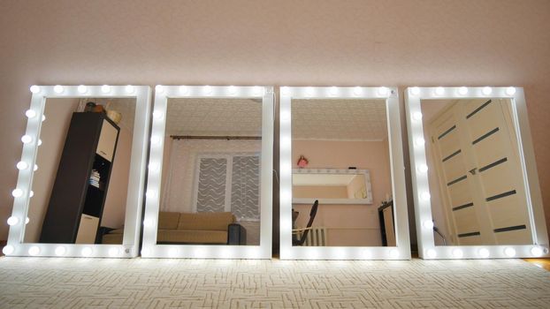 Four make-up mirrors stand in the room and are lit. Mirrors turn on in turn