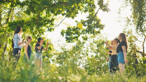 Cheerful schoolgirls play ball on a summer evening outside the city