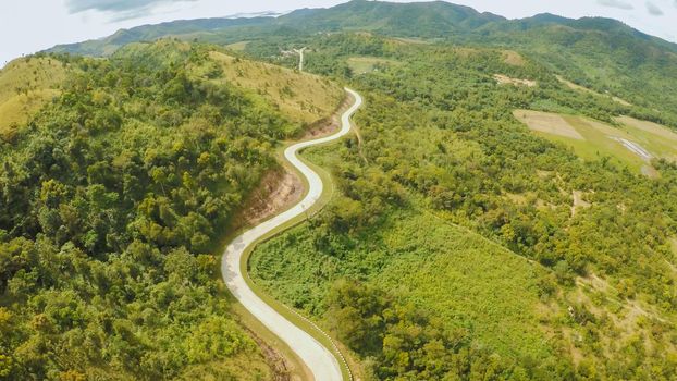 A long and winding road passing through green hills. Busuanga island. Coron. Aerial view. Philippines