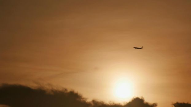 Take off the plane in the distance against the background of sunrise or sunset. Silhouette of an airplane. Airplane in the sky at sunset