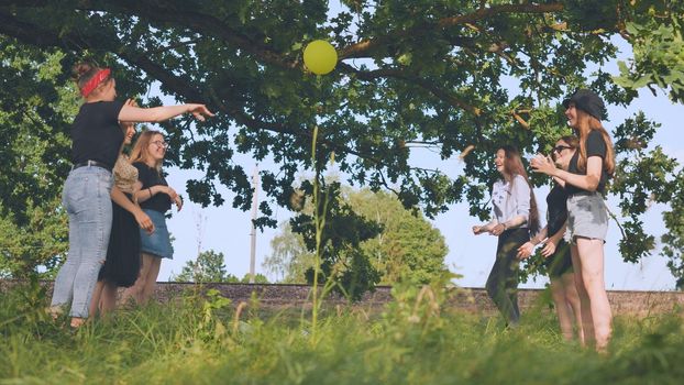 Cheerful schoolgirls play ball on a summer evening outside the city