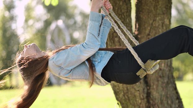 Young beautiful long-haired girl on a rope swing