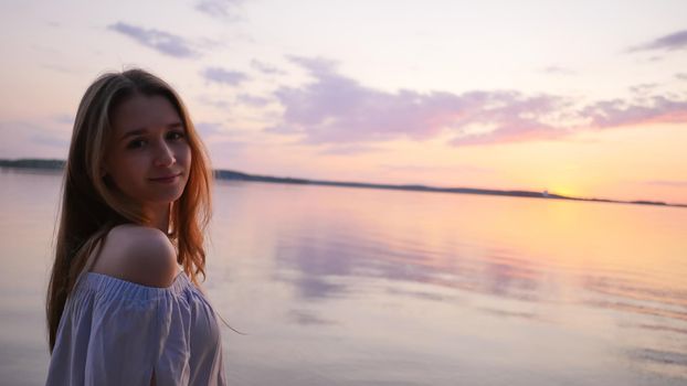 Young girl on the background of the sea and sunset