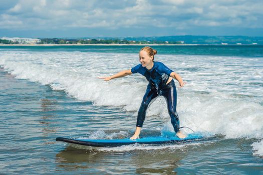 Joyful young woman beginner surfer with blue surf has fun on small sea waves. Active family lifestyle, people outdoor water sport lesson and swimming activity on surf camp summer vacation.