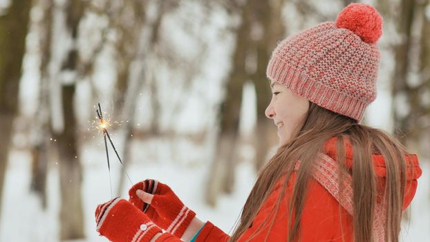 The charming young schoolgirl joyfully holds in her hands a packaged box with a gift in the winter forest. In anticipation of the New Year holidays