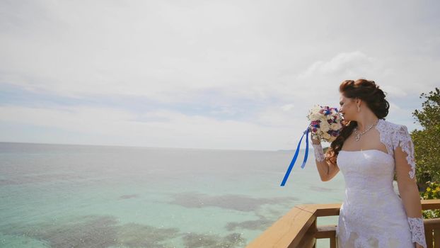 A dazzling bride enjoys happiness from the height of the balcony overlooking the ocean and reefs. Flight of love. Exotic Filipino Tropics. Shooting in motion