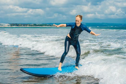 Joyful young woman beginner surfer with blue surf has fun on small sea waves. Active family lifestyle, people outdoor water sport lesson and swimming activity on surf camp summer vacation.