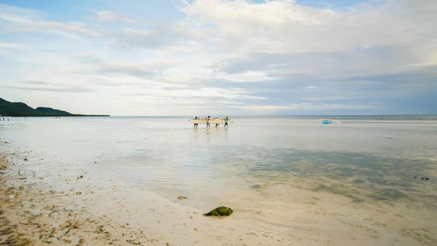 Fishermen carry a boat to the sea. Bohol Island. Philippines